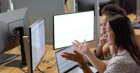 Colleagues analyzing sales data on computer screens in office