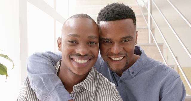Happy diverse gay male couple embracing at home. Togetherness, relationship, love and domestic life, unaltered.