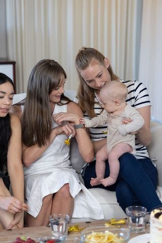 Diverse friends connecting while holding infant using smartwatch