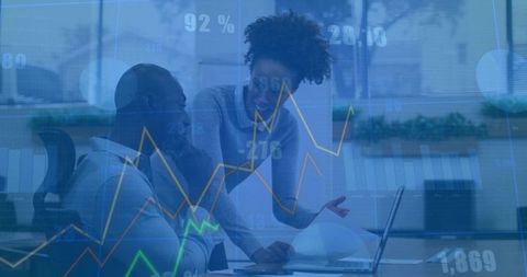 Diverse Team Analyzing Financial Graphs Over Laptop in Office