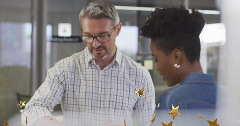 Reviewing documents together in modern glass office with gold star celebration accent