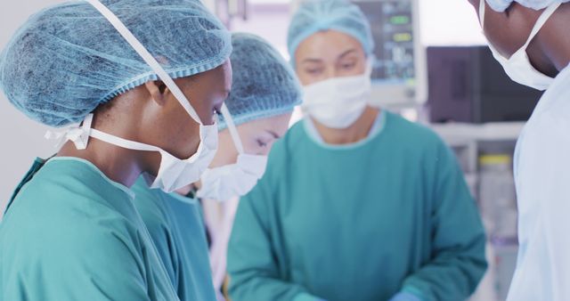 Image of african american female surgeon looking to camera during operation with diverse colleagues. Hospital, medical and healthcare services.