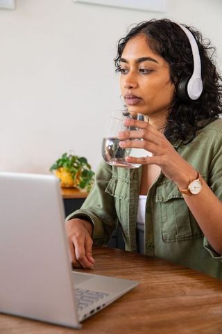 Focused Indian Woman with Headphones Using Laptop in Home Office