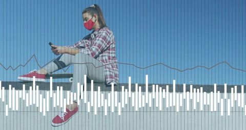 Young woman wearing red mask sitting on ledge scrolling smartphone with skateboard