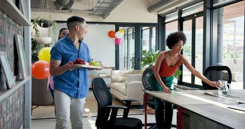 Office staff clearing after party with smiles and laughter