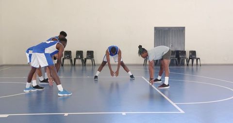 Teammates Stretching for Basketball Practice on Indoor Court