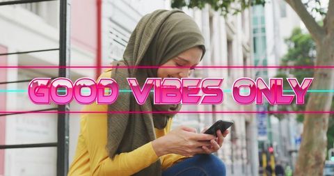 Happy woman engaged with smartphone behind good vibes only text