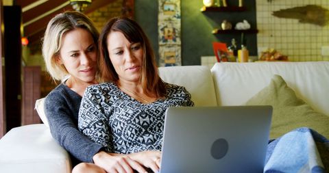 Lesbian Couple Enjoying Time Together on Couch with Laptop