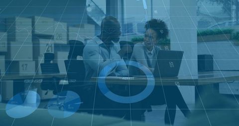 Professionals collaborating over laptop with analytics overlay in modern office