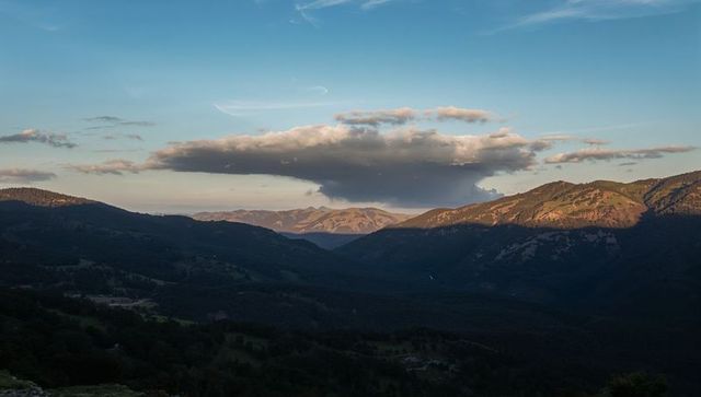 Anvil Cloud Hovering Above Mountain Valley at Golden Hour Casting Dramatic Ridge Shadows