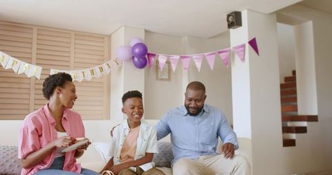 African American family enjoying home birthday with balloons bunting parents and son smiling