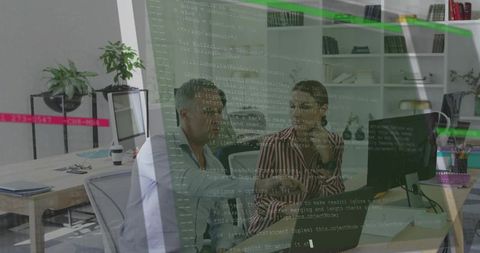 Software engineers reviewing code on computer screen in modern office