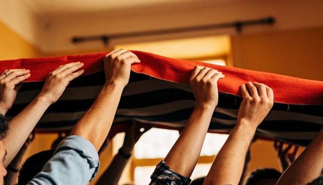Hoisting red fabric canopy together showing teamwork and collaboration in living room