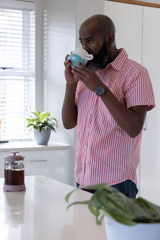 Senior Man Enjoying Morning Coffee at Bright Kitchen Island