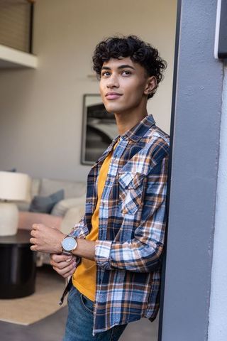 Man in plaid shirt checking watch in modern living room