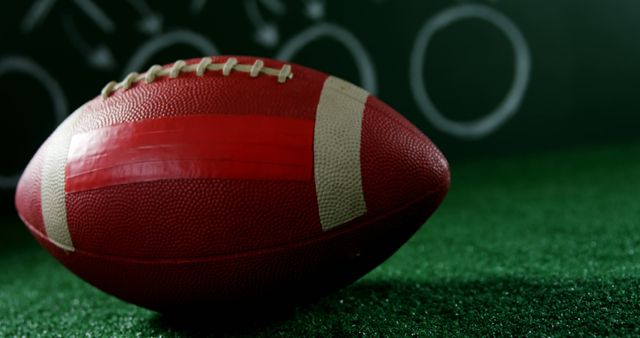 Close-up view of an American football resting on a green field with a strategic play diagram in the background. Perfect for illustrating sports strategies, teamwork, and game planning. Ideal for sports blogs, coaching materials, and promotional content for football-related events or products.