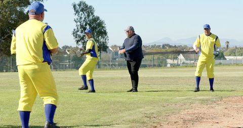 Diverse Men Practicing Baseball in Bright Yellow Uniforms on Suburban Field