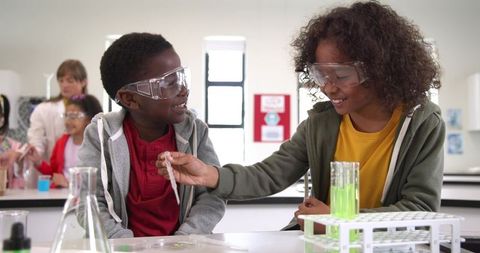 Diverse boys experimenting with green liquid in science classroom