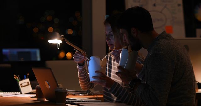 Team Collaborating Late and Eating Takeout Food in Office Under Dim Light - Download Free Stock Images Pikwizard.com