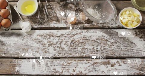 Rustic baking flatlay on floured wooden tabletop with eggs, butter and utensils