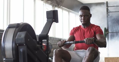 Focused Athlete Training on Rowing Machine in Gym