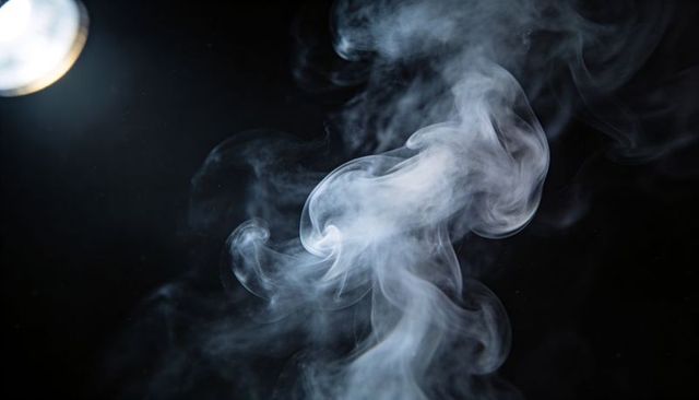 Swirling smoke plumes drifting over dark backdrop with studio light highlighting texture