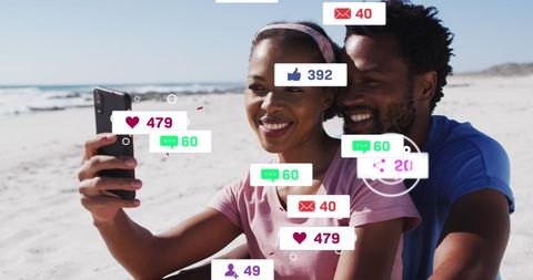 Joyful Couple Engaging on Social Media While Relaxing on Beach