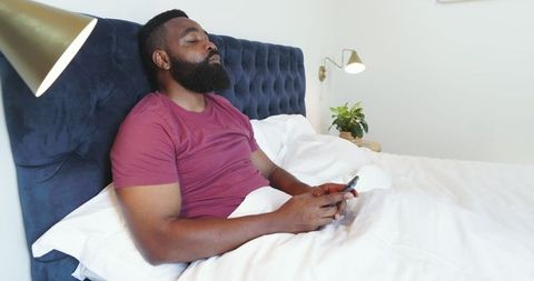 Relaxed Man Browsing Smartphone in Cozy Bedroom Setting