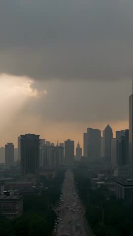 Vertical cinematic cityscape with clouds parting and sunbeam piercing downtown avenue