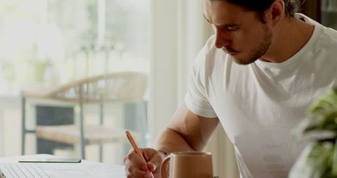 Focused young man working remotely at home office desk