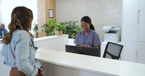 African american receptionist smiling while checking in patient at modern clinic front desk