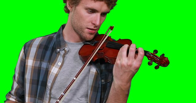 Young man in plaid shirt playing violin on a green screen background. Potential uses include music tutorials, educational materials, promotional content for music education, or graphic design projects requiring isolated subjects with transparent backgrounds.