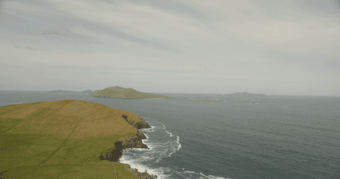 Transparent blue waters and green cliffs meeting ocean horizon