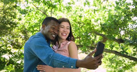 Happy Multiracial Couple Taking Selfie in Sunny Garden