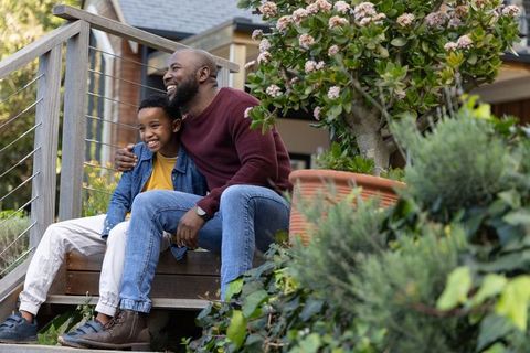 African american father and son sitting on porch steps smiling, sharing outdoor moment