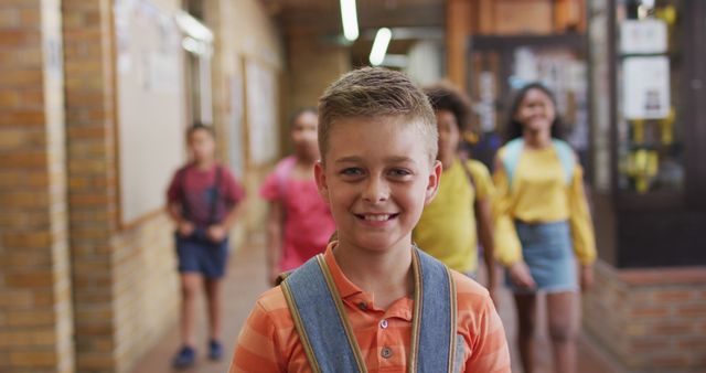 Portrait of happy caucasian schoolboy standing in corridor looking at camera. children in primary school.