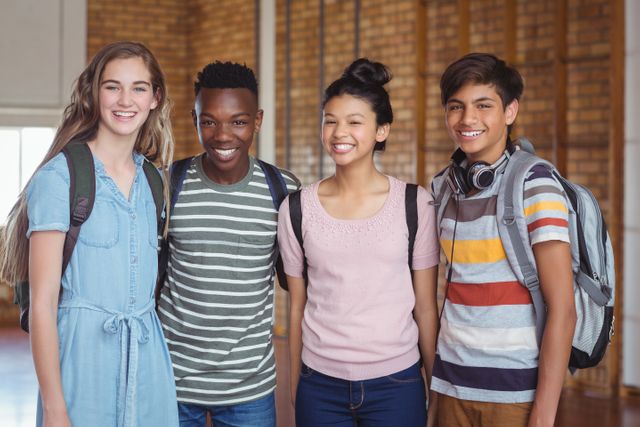 This image shows a diverse group of happy students standing together in a school campus. They are smiling and carrying backpacks, indicating they are ready for school or classes. This image can be used for educational materials, school brochures, websites, and advertisements promoting diversity, friendship, and education.