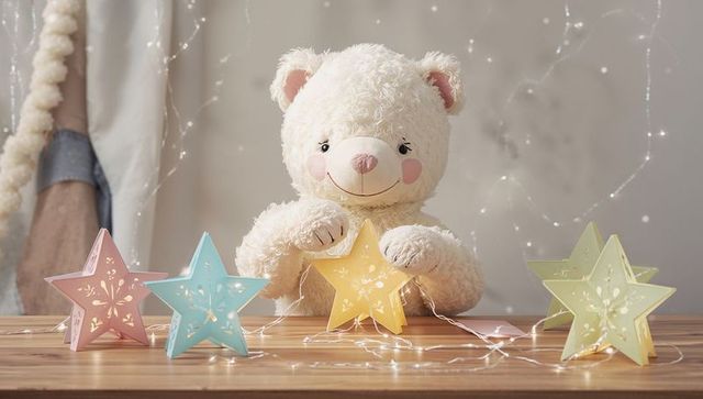 Teddy bear holding glowing star lantern on nursery table with pastel fairy lights