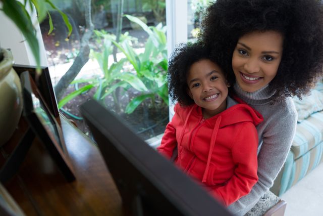 Mother and daughter sitting at piano, smiling while playing music together. Ideal for use in family-oriented content, parenting blogs, educational materials, and advertisements promoting musical instruments or family activities.