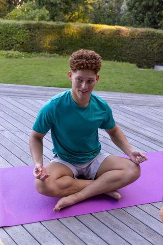 Young Man Meditating Outdoors on Purple Yoga Mat for Mindfulness