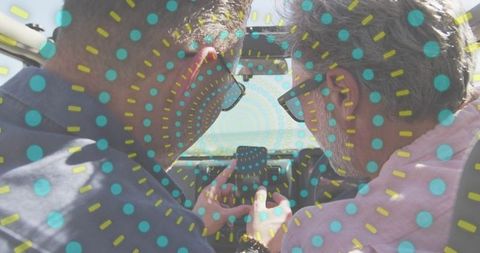 Two men leaning over smartphone in convertible, wearing sunglasses, turquoise dotted overlay