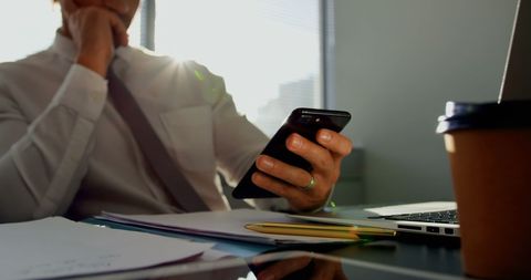 Professional Businessman Using Smartphone in Sunlit Office