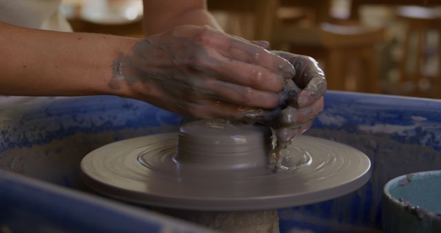 Perfect for websites or marketing materials that focus on arts and crafts, pottery classes, or creative hobbies. This image captures the artistic process, showcasing the detailed work and skill involved in pottery making.