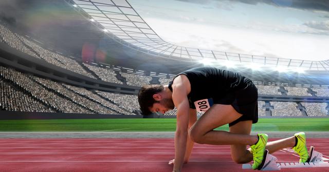 Male sprinter in starting position on athletic track in a crowded stadium. Great for illustrating sportsmanship, endurance, fitness campaigns, motivational content, sporting events promotions, athletic apparel ads, and track and field articles.