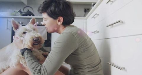 Affectionate Woman Stroking Terrier in Cozy Kitchen Environment