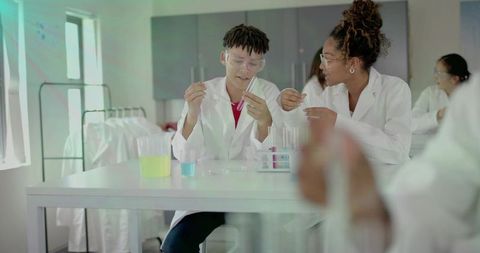 Students collaborating in school science lab conducting colorful chemistry experiments with test tub