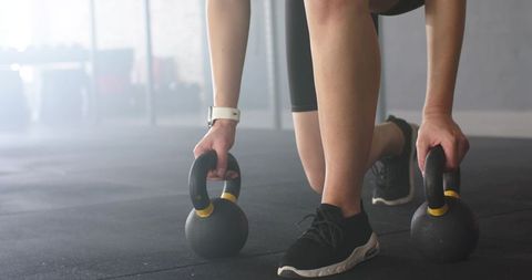 Woman preparing for kettlebell workout at gym with focused stance