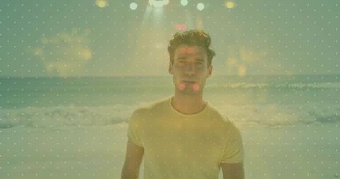 Man standing at sunlit beach wearing yellow t-shirt with lens flare and bokeh
