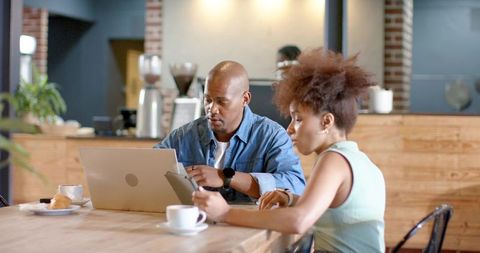 African american colleagues collaborating on laptop and smartphones in cozy urban cafe