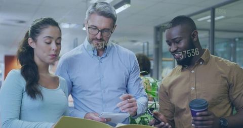 Diverse team reviewing notes and smartphone in modern open-plan office collaboration